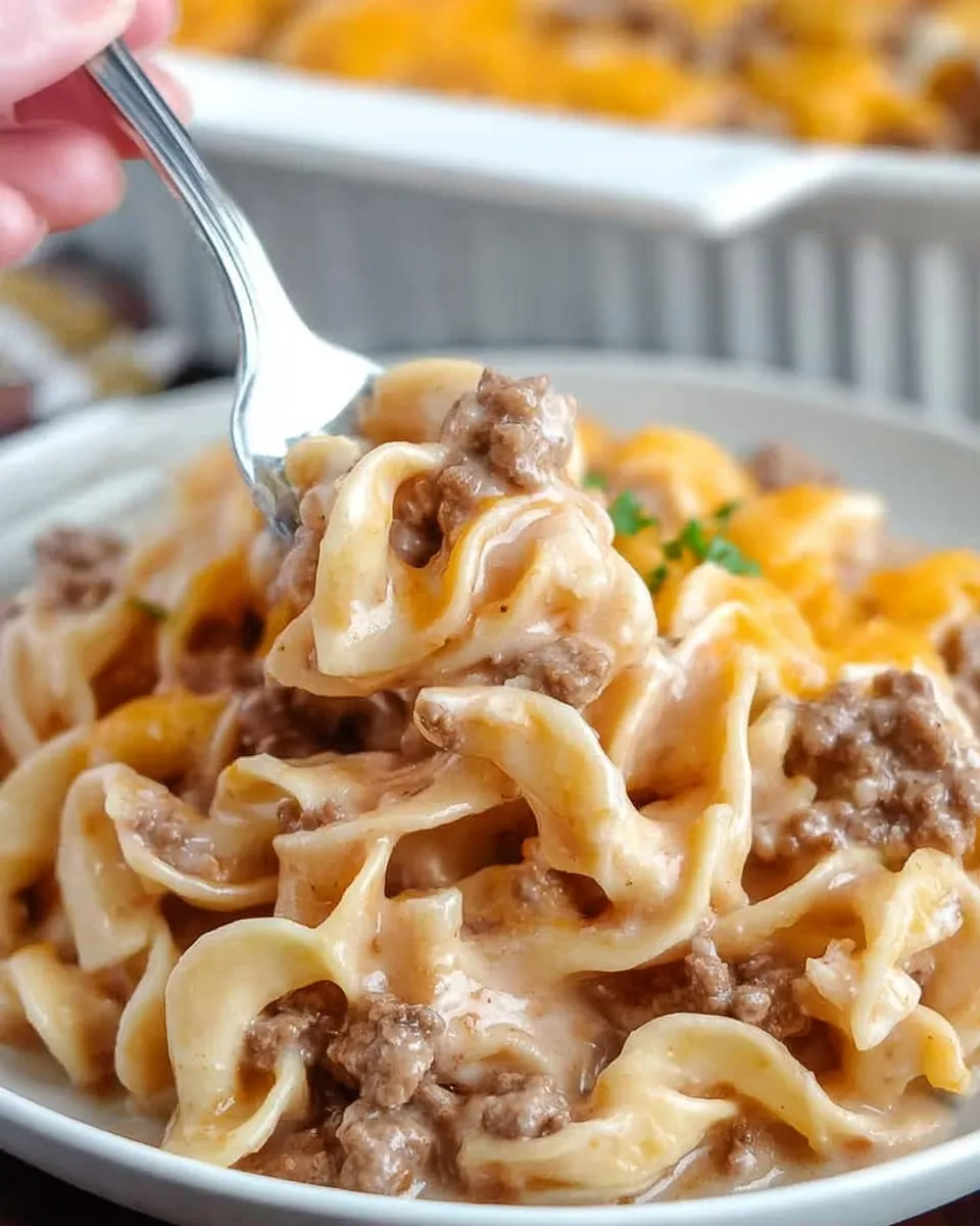 tender egg noodles and savory ground beef Close-up of a fork lifting a creamy bite of Hearty Amish Country Casserole, featuring tender egg noodles and savory ground beef.