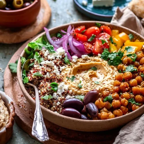Mediterranean protein bowl with crispy roasted chickpeas, tri-color quinoa, kalamata olives, and creamy hummus topped with sesame seeds.