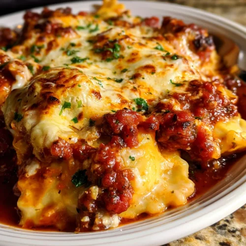 Baked Crockpot Ravioli with cheese, meat sauce, and herbs, golden-brown topped with melted cheese and fresh parsley.