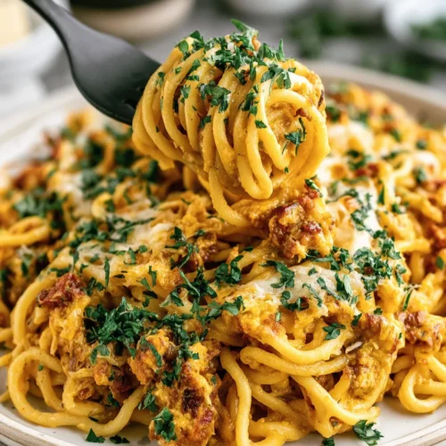Creamy, cheesy spaghetti with herbs, topped with parsley, served on a white plate.