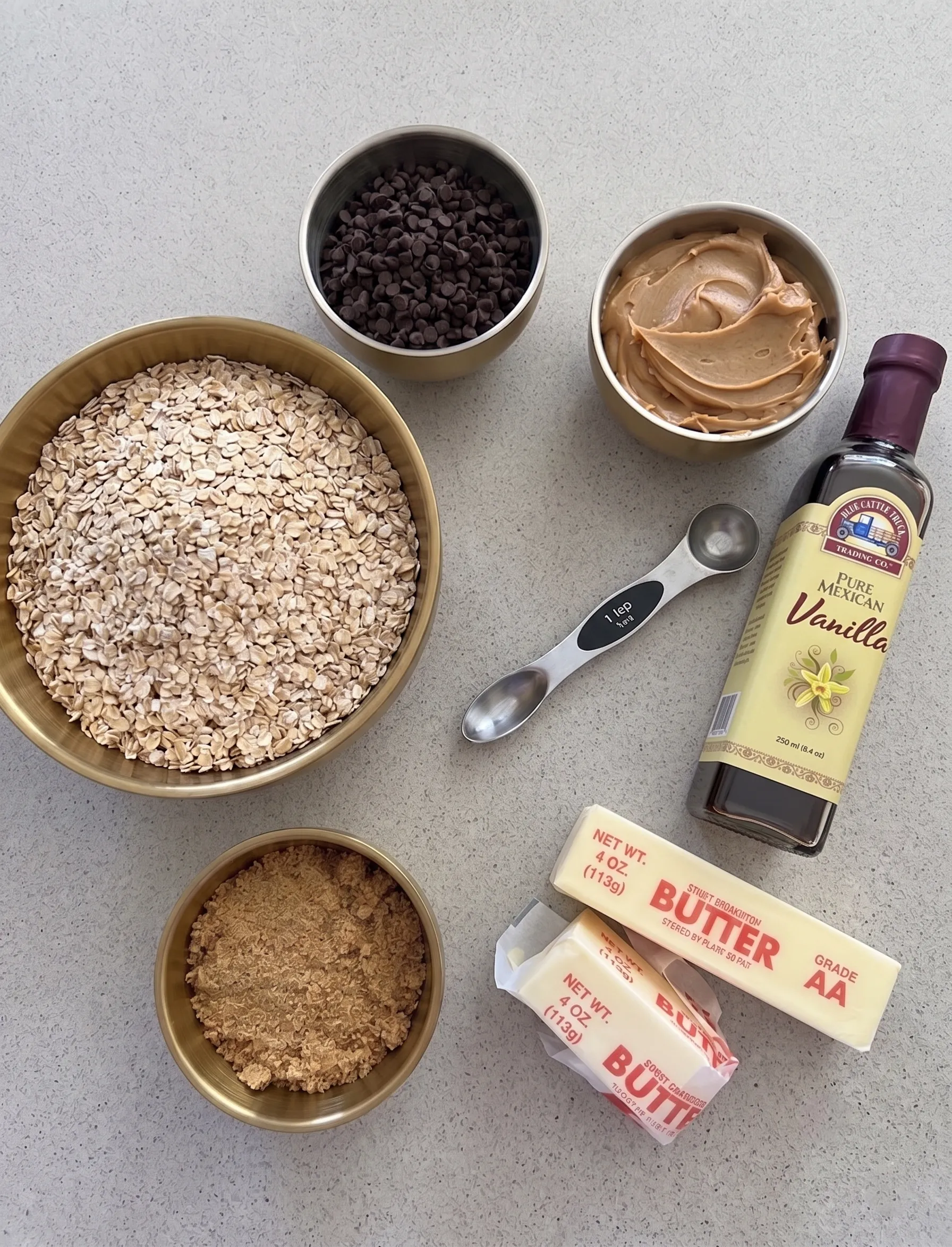 Ingredients for a cookie recipe: oats, chocolate chips, peanut butter, vanilla, brown sugar, and butter.