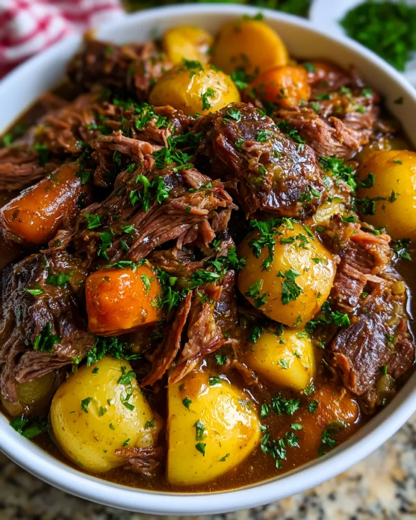 Slow Cooker Pot Roast: Hearty beef stew with potatoes and carrots, garnished with parsley, served in a white bowl.